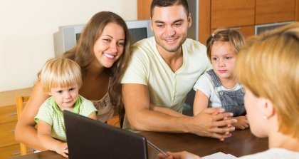 Eine Familie mit Kindern lässt sich das Kita Portal am Laptop von einer Erzieherin erklären.