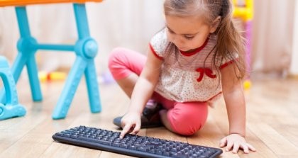 Ein Kind in der Kita drückt auf eine Computertastatur.