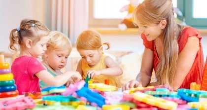 Eine Erzieherin betreut drei Kinder in der Kita beim Spielen.