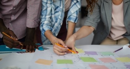 Vier Menschen zusammen an einem Schreibtisch, die planen und Tabellen auswerten