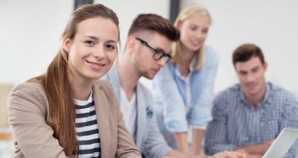 Junge Frau im Büro mit Kollegen im Hintergrund