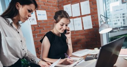 Zwei Frauen notieren etwas und arbeiten am Schreibtisch