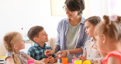 Vier Kinder spielen mit einer pädagogischen Fachkraft