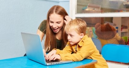 Erzieherin und kleiner Junge sitzen vor einem Laptop